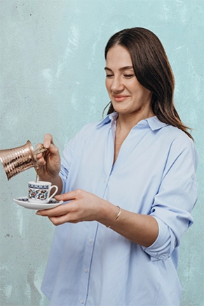 Frau schenkt Kaffee in eine türkische Mokkatasse ein