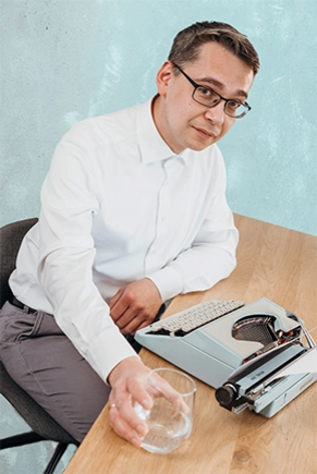 Mann an Schreibtisch mit Schreibmaschine