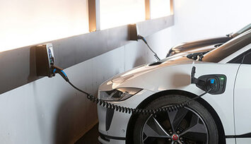 weißes E-Auto wird im Parkhaus geladen