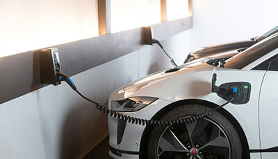 weißes E-Auto wird im Parkhaus geladen