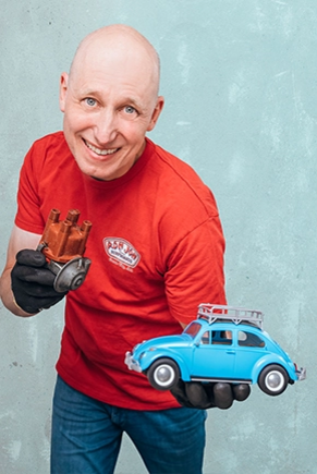 Mann in rotem Shirt hält ein Modellauto in der Hand
