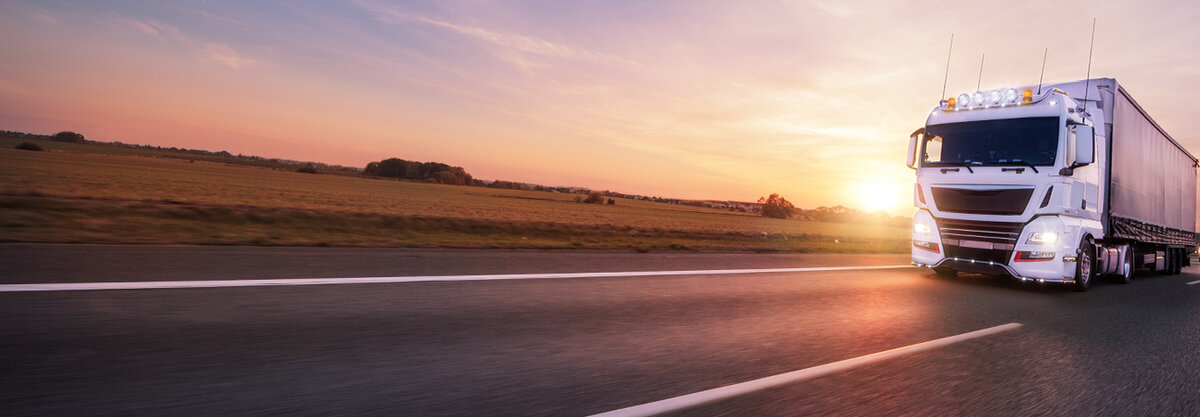 LKW fährt auf leerer Straße vor Sonnenuntergang