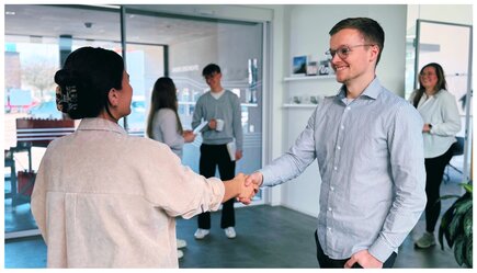 [Translate to English:] Eine Frau gibt in einer Eingangshalle einem Mann die Hand