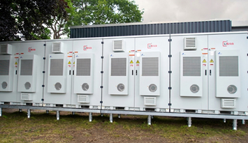 A row of BESS units in a meadow
