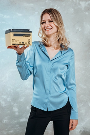 Frau in blauer Bluse hält Batterie in einer Hand