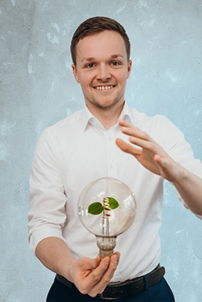 Mann hält Glühbirne mit Pflanze in die Kamera