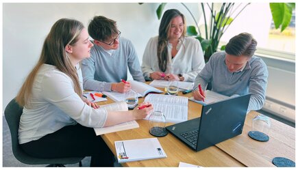 [Translate to English:] 4 Menschen sitzen um einen Laptop und arbeiten gemeinsam an einem Thema